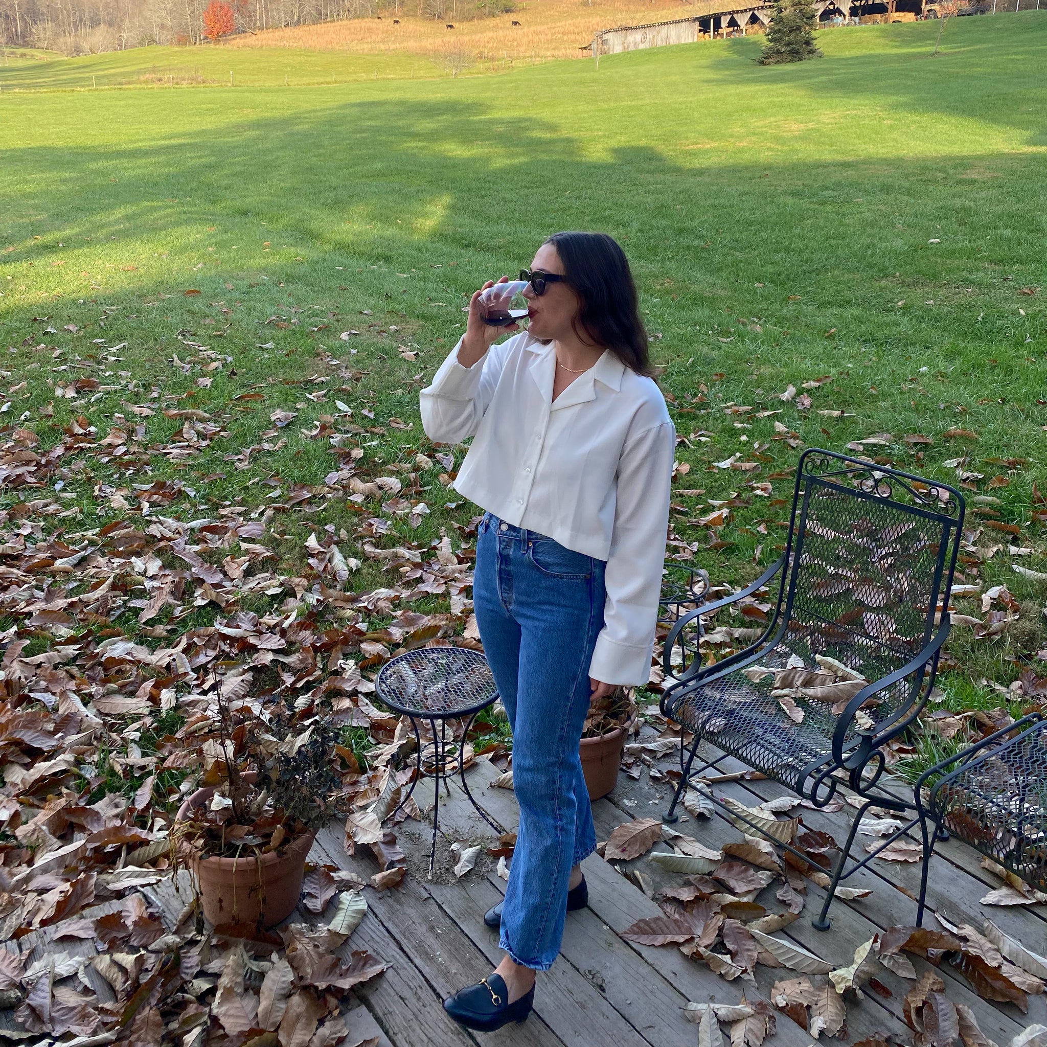 Social media shot of the Elvine long sleeve button up collared blouse in white, paired with high waisted jeans, loafers and sunglasses for a perfect fall outfit.