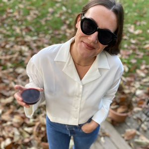 A social media image featuring the elvine button up collared blouse in white, paired with black sunglasses and high waisted jeans.