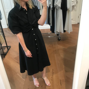 Social media selfie of the Kristen midi button up collared dress in black with twist detailing at the waist and puff sleeves. Paired with strappy heels.