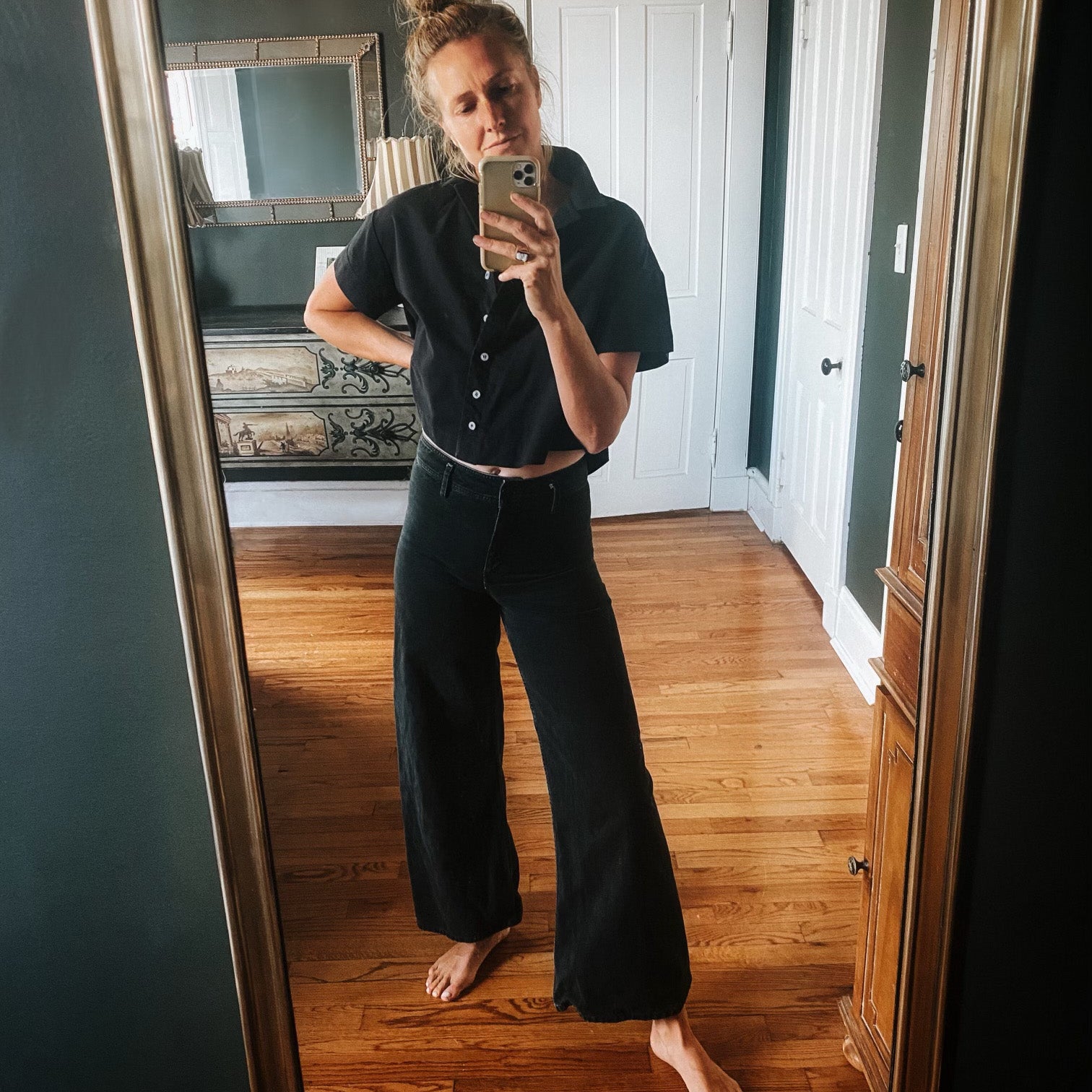 A social media selfie featuring the Tanvi button up collared crop top in black. Styled with black high waisted flare jeans.